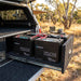 Two Renogy Core Mini 100Ah batteries in a 4WD canopy drawer, cabling connected, tailgate open to a bush campsite