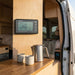 Renogy battery monitor mounted on a van conversion wall above a timber bench