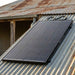 Renogy 200W ShadowFlux solar panel mounted on a corrugated-iron shed roof in golden-hour light
