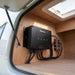Renogy DC-DC charger mounted on a plywood bulkhead inside a caravan storage locker with a neat cable loom