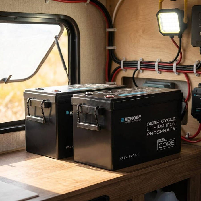 Two Renogy Core Mini 200Ah LiFePO4 batteries in a camper trailer electrical bay, cabling and LED worklight visible