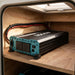 Renogy 3000W inverter mounted in a caravan storage locker with cable loom and daylight through a hatch