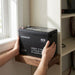 Hands lowering the Renogy 48V 50Ah battery onto a mounting shelf in a home battery cabinet