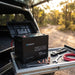 Renogy Core Mini 100Ah battery in an open battery box in a 4WD canopy drawer, tailgate open to a bush track