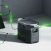 Portable power station connected to solar panels indoors with glowing green power lines.