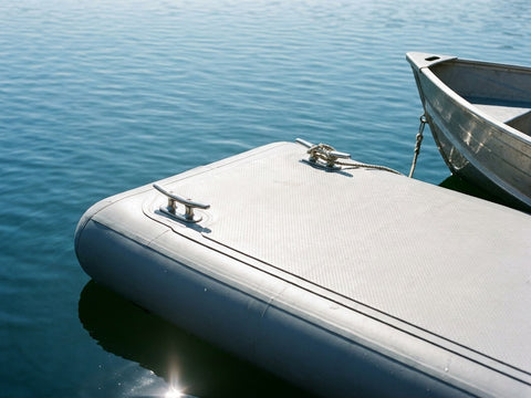 An inflatable pontoon with a tinnie tied up on a calm lake