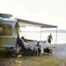 Thule Omnistor 6300 Electric 12V Awning providing shelter and comfort for a family camping by the lakeside, creating the perfect outdoor retreat.