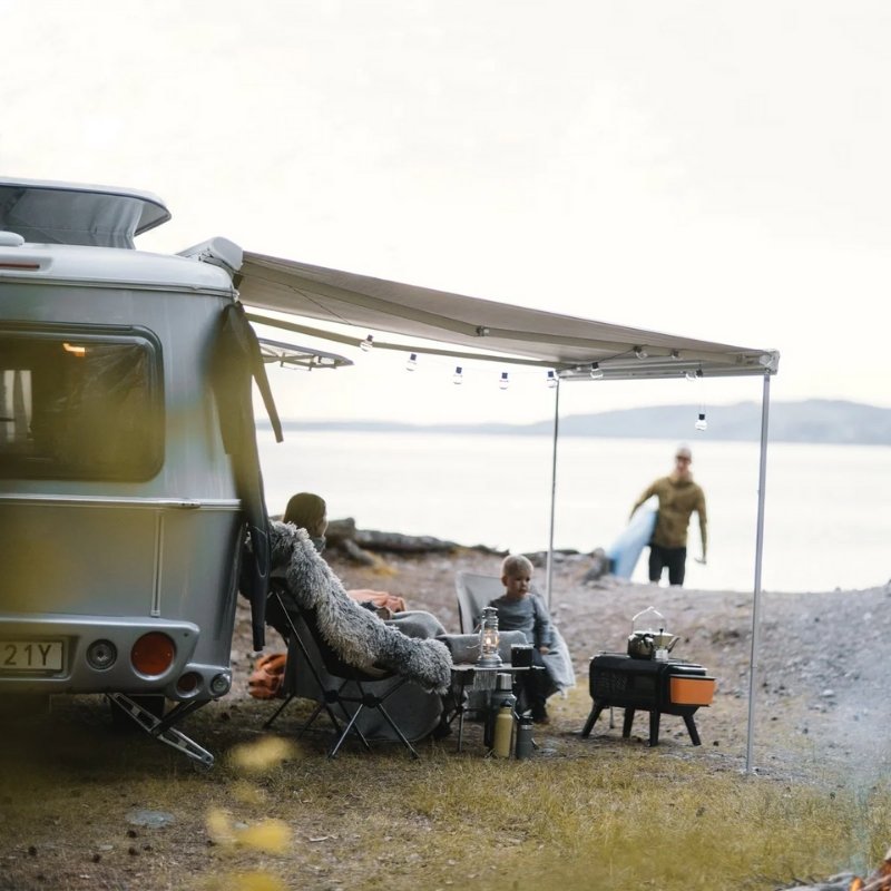 Thule Omnistor 6300 Electric 12V Awning providing shelter and comfort for a family camping by the lakeside, creating the perfect outdoor retreat.