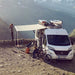 Thule Omnistor 6300 Electric 12V Awning set up at a sunny campsite, offering the perfect amount of shade for outdoor activities and relaxation.