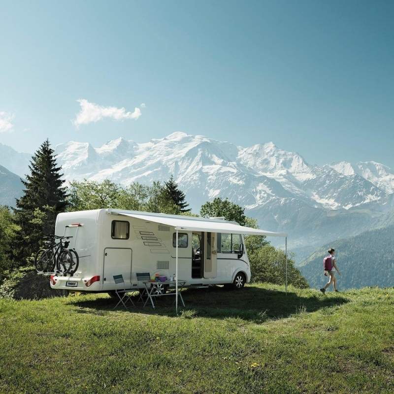 The Thule Omnistor 8000 Electric 230V Awning deployed on an RV at a scenic mountain campsite, providing shelter and comfort.