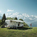 Thule Omnistor 8000 manual awning extended at a scenic mountain campsite, offering protection from the sun while enjoying nature.