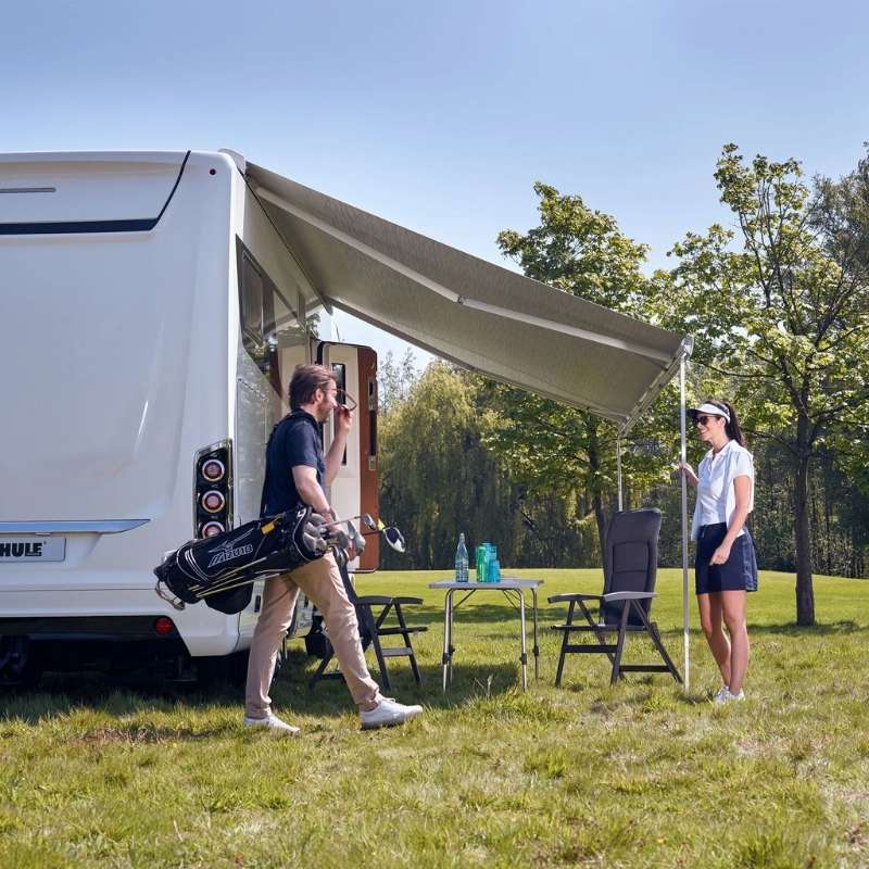 Thule Omnistor 9200 awning extended on a motorhome with outdoor chairs and table, showing campsite shade setup from the awning manual.